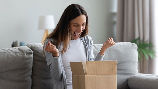 Deals for key workers young woman excited opening parcel